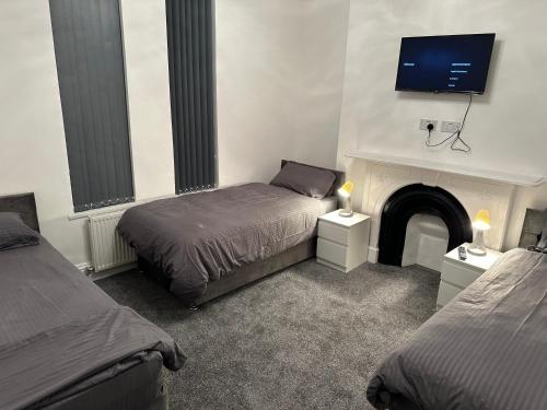a bedroom with two beds and a tv over a fireplace at Juz Apartments Manchester airport in Altrincham