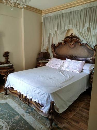 1 dormitorio con 1 cama grande y cabecero de madera en شقه فاخره للايجار بكامب شيزار, en Alejandría
