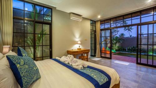 Lavina Ubud Villas في أوبود: غرفة نوم بسرير كبير ونوافذ كبيرة