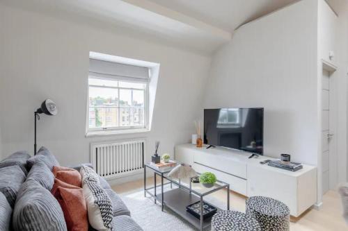 a living room with a couch and a tv at Stylish 1BD Flat 5 Mins to Harrods- Knightsbridge in London