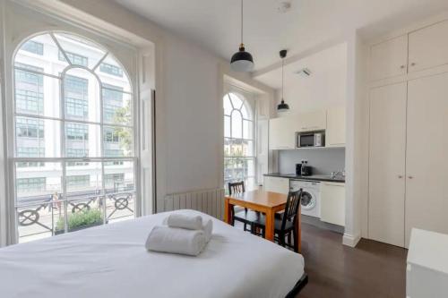 a white bedroom with a large bed and a kitchen at Incredibly Located Studio Flat - Camden Town in London