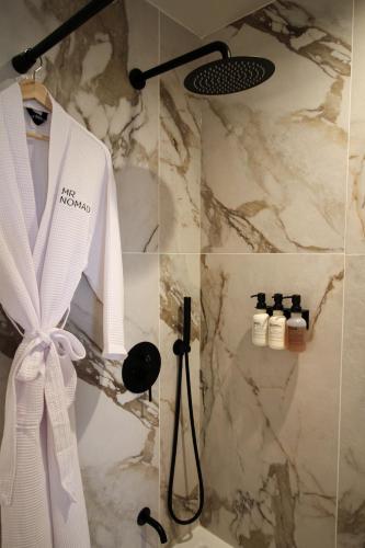 a bathroom with a shower with a white robe on a wall at MrNomad Boutique Hotel Parisian Townhouse in Dallas