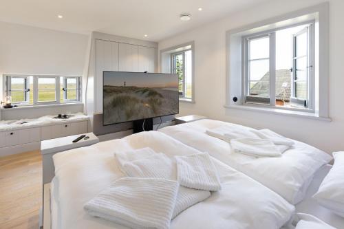 a white bedroom with a large white bed and a flat screen tv at Westport in List