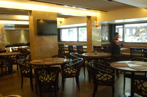 comedor con mesas y sillas y TV en The President-A Boutique Hotel en Ahmedabad