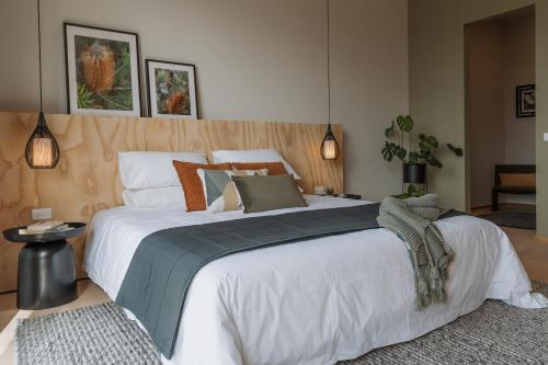um quarto com uma cama grande com lençóis brancos e almofadas em Jacquina - Yarra Valley em Healesville