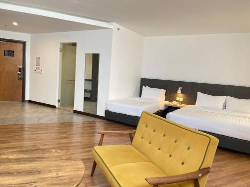 une chambre d'hôtel avec deux lits et une chaise dans l'établissement Win Hotel, à Sibu