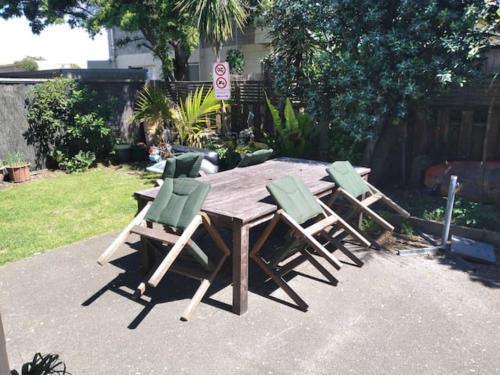 a wooden table with four green chairs around it at sun, sand & surf, its all across the road in Mount Maunganui