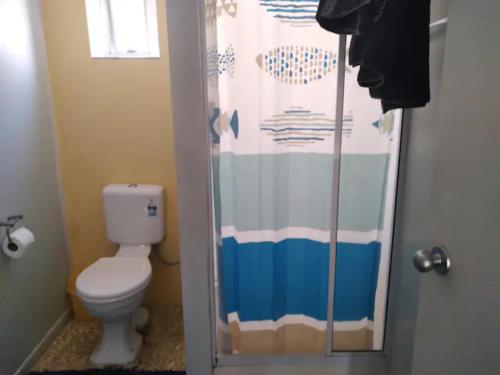 a bathroom with a toilet and a shower curtain at sun, sand & surf, its all across the road in Mount Maunganui