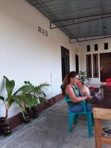 a woman sitting on a chair holding a baby at Riung Tiga Empat Tujuh Guesthouse in Riung