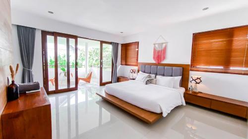 ein Schlafzimmer mit einem großen weißen Bett und Fenstern in der Unterkunft Casa Naima Petitenget Villa in Seminyak