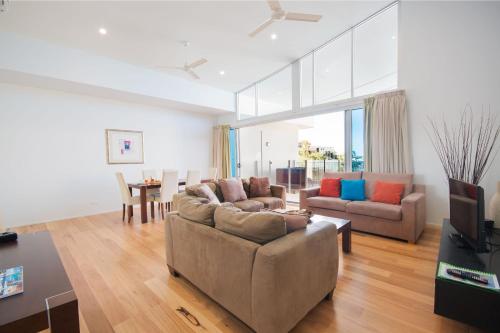 a living room with two couches and a table at Azure Sea Whitsunday Resort in Airlie Beach