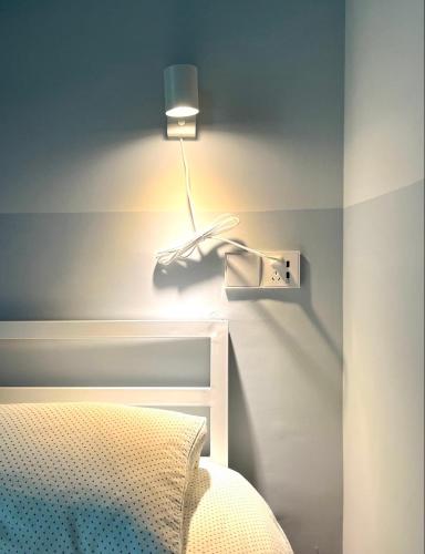 a bedroom with a bed with a lamp on the wall at Shenzhen Loft Youth Hostel in Shenzhen