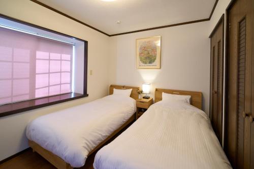 two beds in a small room with a window at Suite Villa Izukogen Mikanno-Hanasaku-Shiroiie in Ito