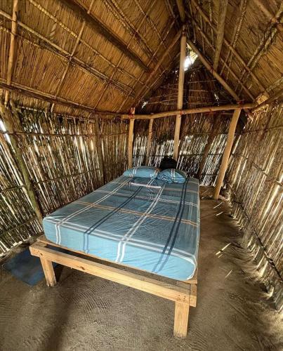 a bed in a straw hut in a room at Cabañas tradicionales en isla Aroma in Warsobtugua