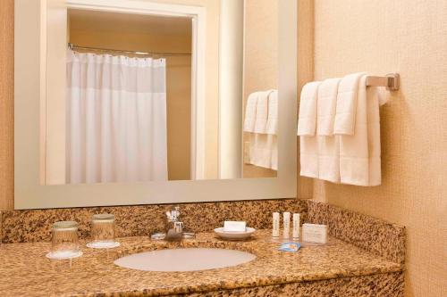 SpringHill Suites Boston Peabody في بيبودي: حمام مع حوض ومرآة ومناشف