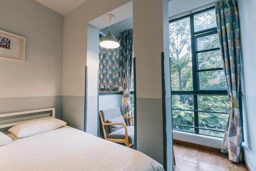 a bedroom with a bed and a chair and a window at Shenzhen Loft Youth Hostel in Shenzhen