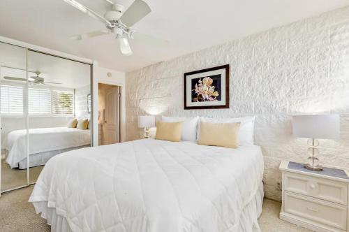 a white bedroom with a large bed and a mirror at Condos in Kana'i A Nalu in Wailuku