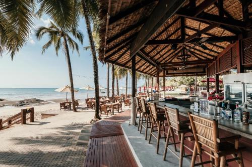 um bar na praia com palmeiras e o oceano em Khaolak Laguna Resort em Khao Lak