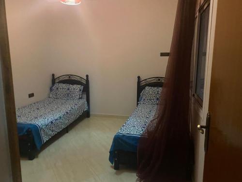 duas camas num pequeno quarto com uma porta em Appartement à cape de l’eau en plein centre em Ras El Ma