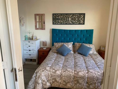 1 cama con cabecero azul en un dormitorio en Departamento Playa Las Cadenas, en Algarrobo