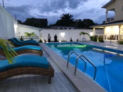 a swimming pool with chairs next to a house at villa piscine timbamba in Pointe-Noire