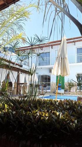 a white umbrella and some plants and a pool at Pousada Love Piri in Pirenópolis