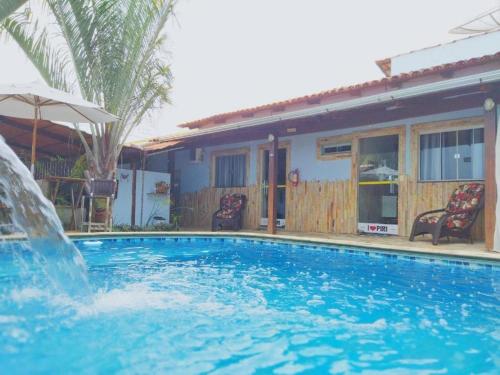 a swimming pool with a waterfall in front of a house at Pousada Love Piri in Pirenópolis