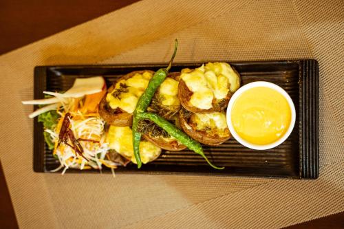 a plate of food with shrimp and a bowl of sauce at Hotel Black Diamond - Transit Point Inside Hotel in Kathmandu