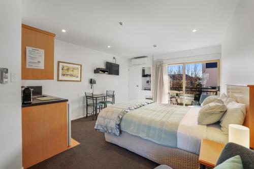 a bedroom with a bed and a desk and a window at Lorenzo Motor Lodge in Christchurch