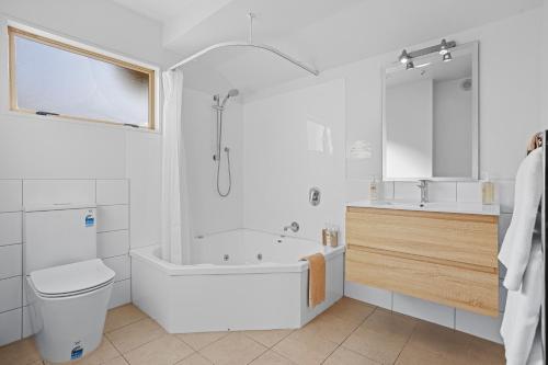 a bathroom with a tub and a toilet and a sink at Lorenzo Motor Lodge in Christchurch