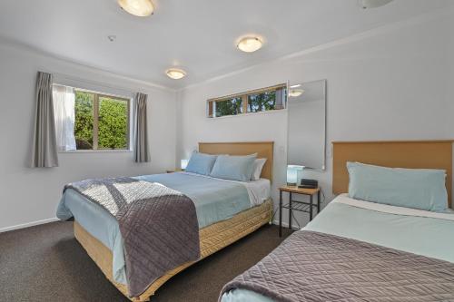 a bedroom with two beds and two windows at Lorenzo Motor Lodge in Christchurch