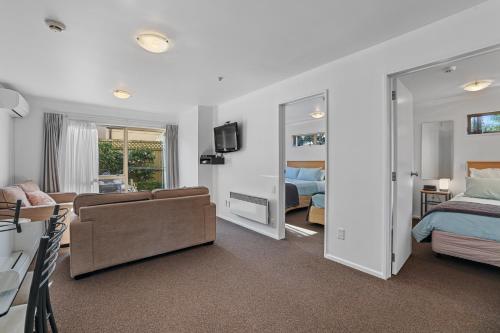 a bedroom with a bed and a living room with a couch at Lorenzo Motor Lodge in Christchurch