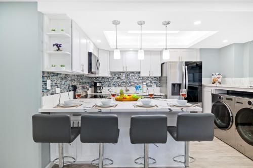 a kitchen with white cabinets and a kitchen island with chairs at Fully Renovated 2BR and 2BA Near Waikiki Beach with Parking in Honolulu