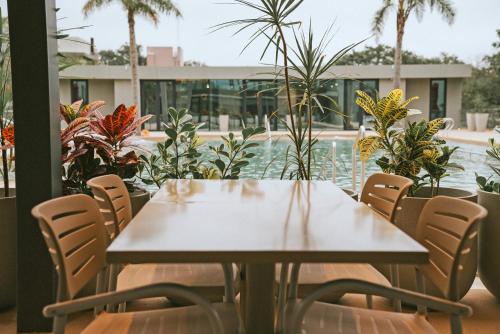 a table and chairs in a patio with plants at Howard Johnson Plaza La Ribera in Resistencia