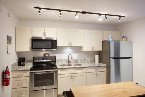 a kitchen with white cabinets and a stainless steel refrigerator at South Maui 1 BR Guest Suite - Kamaole Beach Area in Wailea