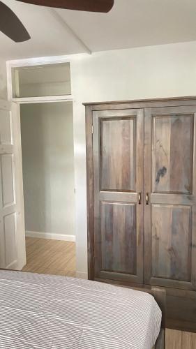 a bedroom with a bed and a wooden cabinet at Travellers Villa in Roseau