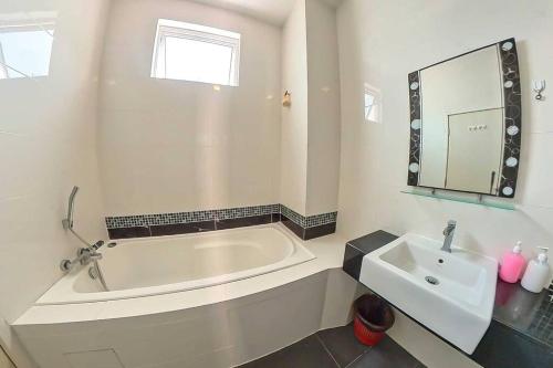 Baño blanco con bañera y lavamanos en Desaru Spacious 6 Rooms Bungalow 22paxes KTV-Billard-BBQ-Netflix, en Kota Tinggi