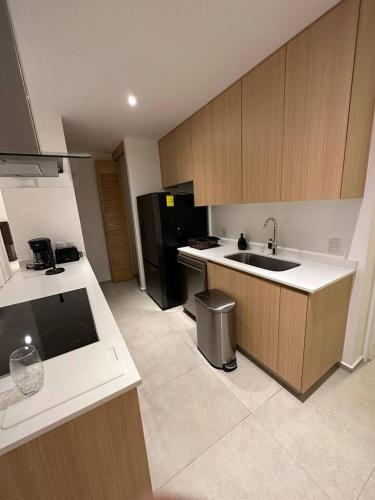 a kitchen with a sink and a black refrigerator at 313 Paraíso frente al mar in Nuevo Vallarta