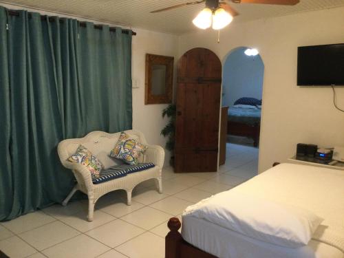 a bedroom with a bed and a chair and a television at Lorna's Cottage in Crown Point