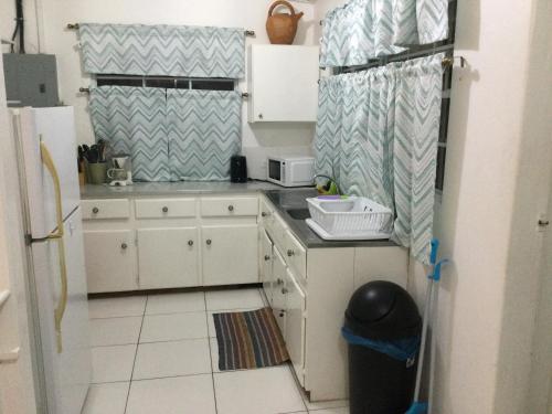 a small kitchen with white cabinets and a refrigerator at Lorna's Cottage in Crown Point