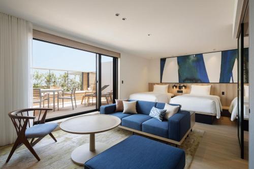 淡路市にあるフェアフィールド・バイ・マリオット・兵庫淡路島東浦の青いソファとベッドルームが備わるホテルルームです。
