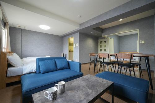 Habitación con sofá azul, cama y mesa. en Residence Hotel KABUTO en Sapporo
