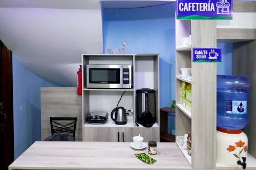 Hostal Valle Andino في El Tambo: مطبخ ألعاب مع طاولة وتلفزيون على رف