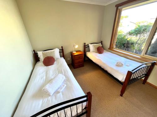 two twin beds in a room with a window at The Hazards Beach Escape in Coles Bay