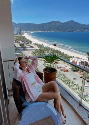 a woman sitting in a chair looking out at the beach at Diamond Sea Hotel in Da Nang