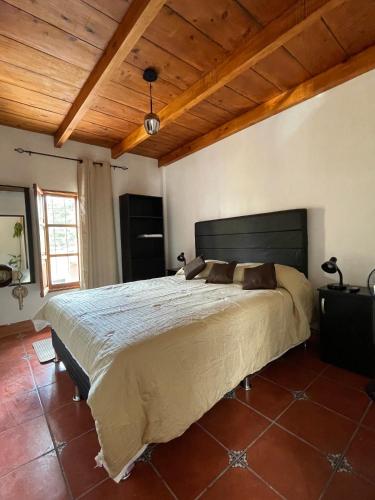 a bedroom with a large bed with a wooden ceiling at Zoola Suites Antigua in Antigua Guatemala