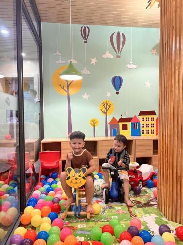 two young boys sitting in a room filled with balls at Diamond Sea Hotel in Da Nang