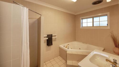 a white bathroom with a tub and a sink at The Major Mitchell Motel in Bourke