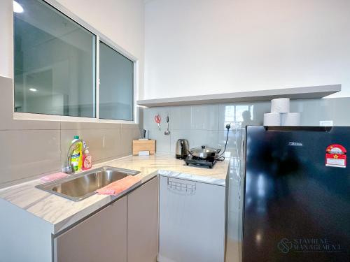 a kitchen with a sink and a refrigerator at Melaka Novo 8 Residence - Jonker Street by Stayrene in Melaka