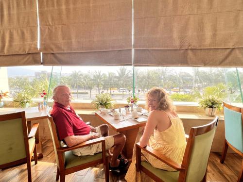 a man and woman sitting at a table in a restaurant at Diamond Sea Hotel in Da Nang